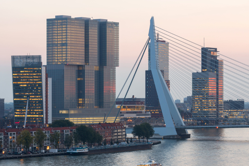 Avondzicht op de skyline van Rotterdam met de Erasmusbrug en hoogbouw langs de Maas. Fotograaf: Ossip van Duivenbode
